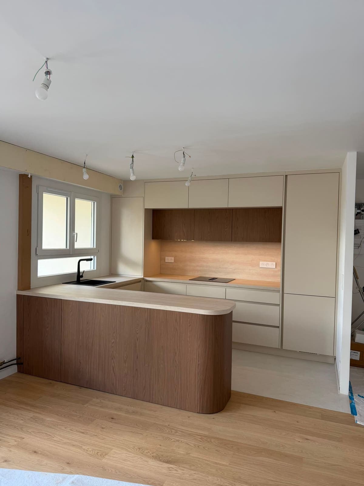 Cuisine claire sur mesure avec îlot central arrondi en bois et colonnes toute hauteur