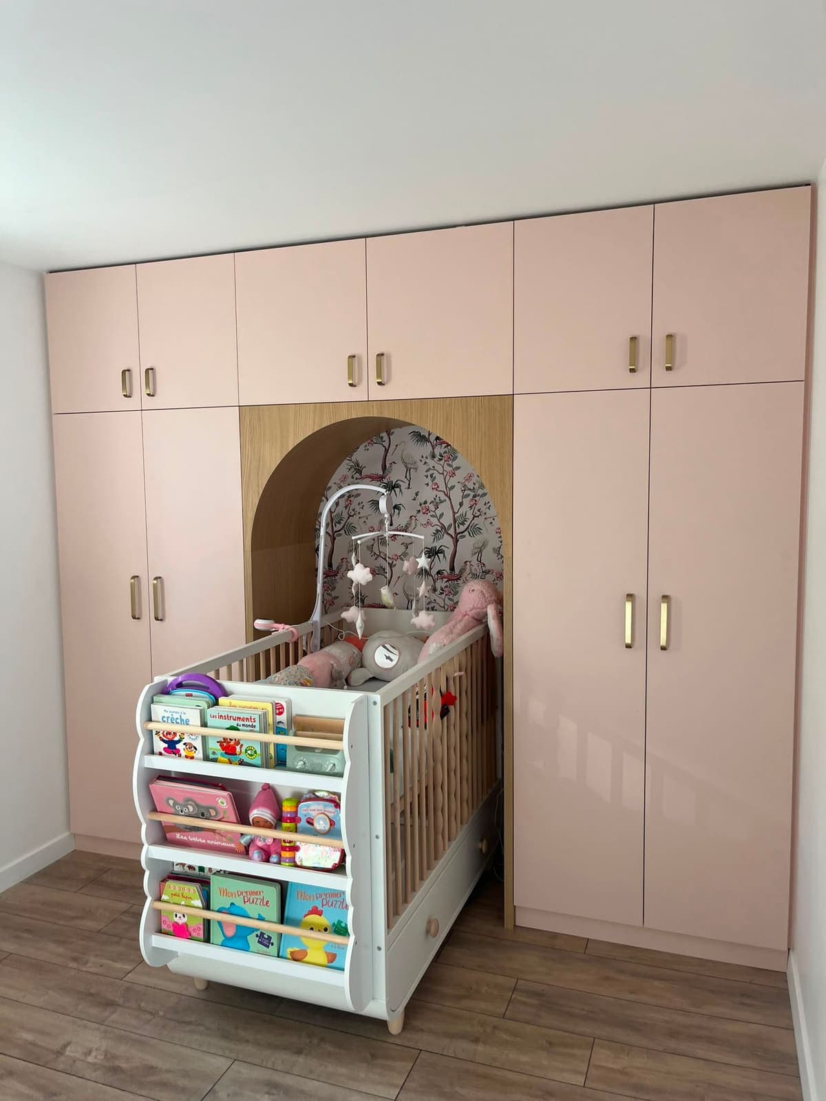 Placards de chambre d'enfant rose poudré encadrant une niche en arche pour le lit