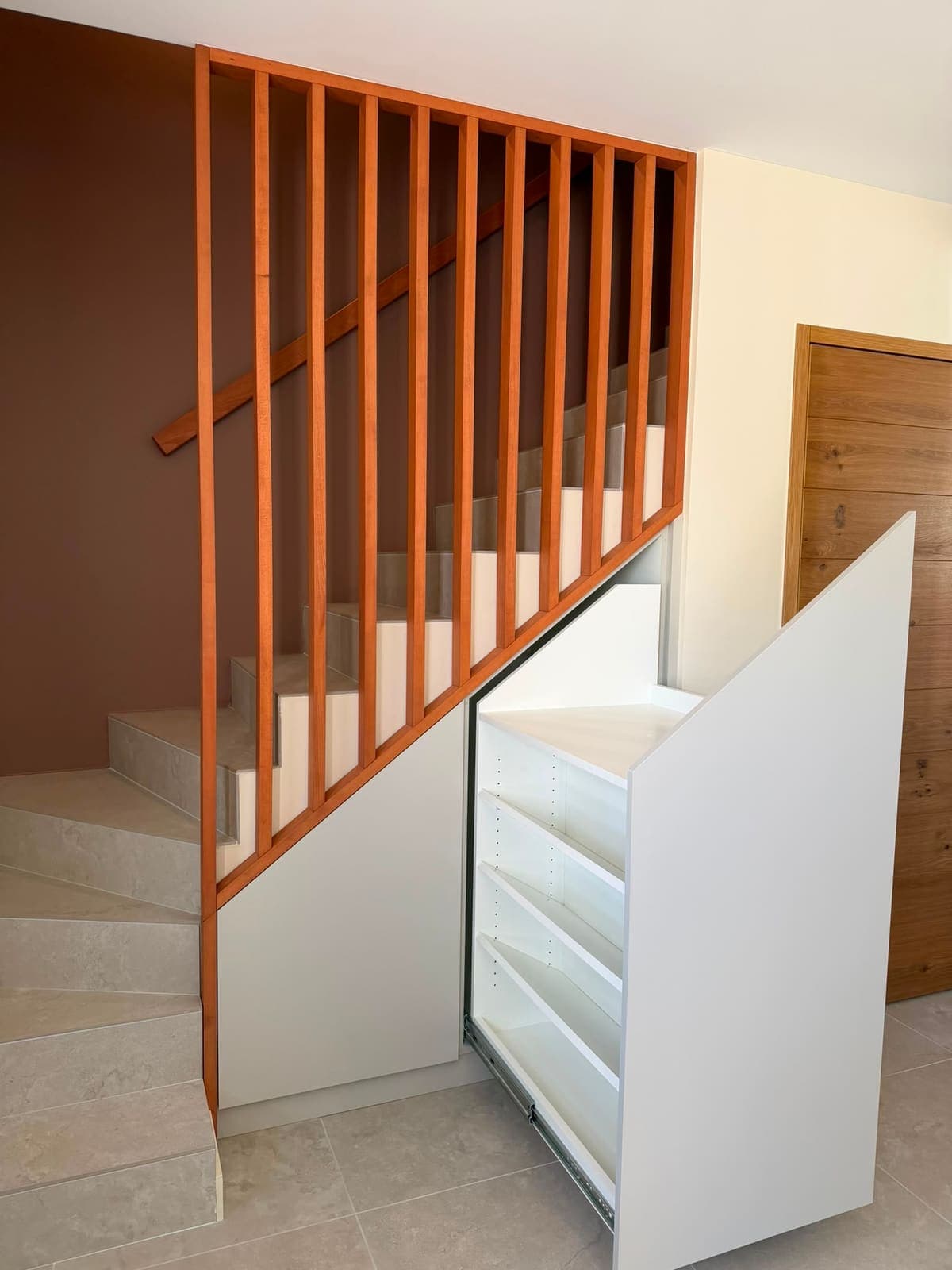 Meuble coulissant sorti de sous un escalier, façade blanche et claustra bois au-dessus