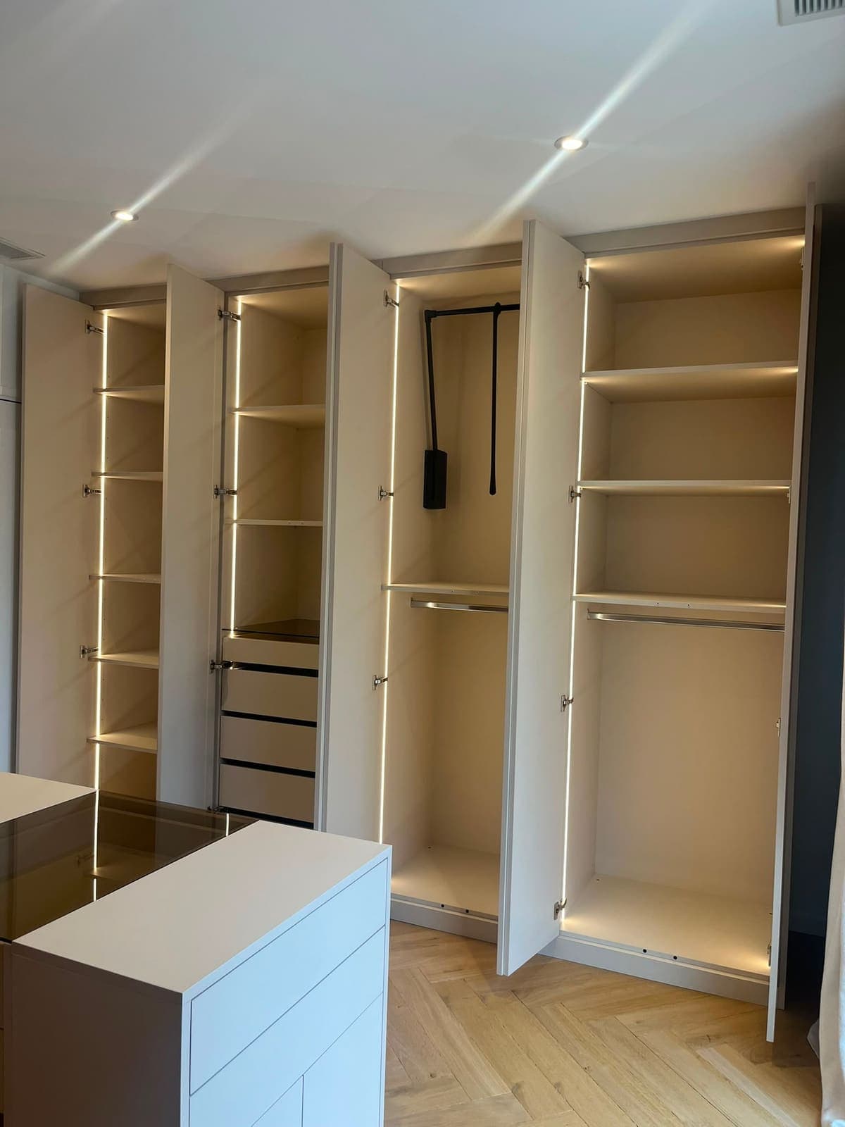 Dressing d'angle portes ouvertes : penderies, tiroirs et étagères éclairés par LED intégrée