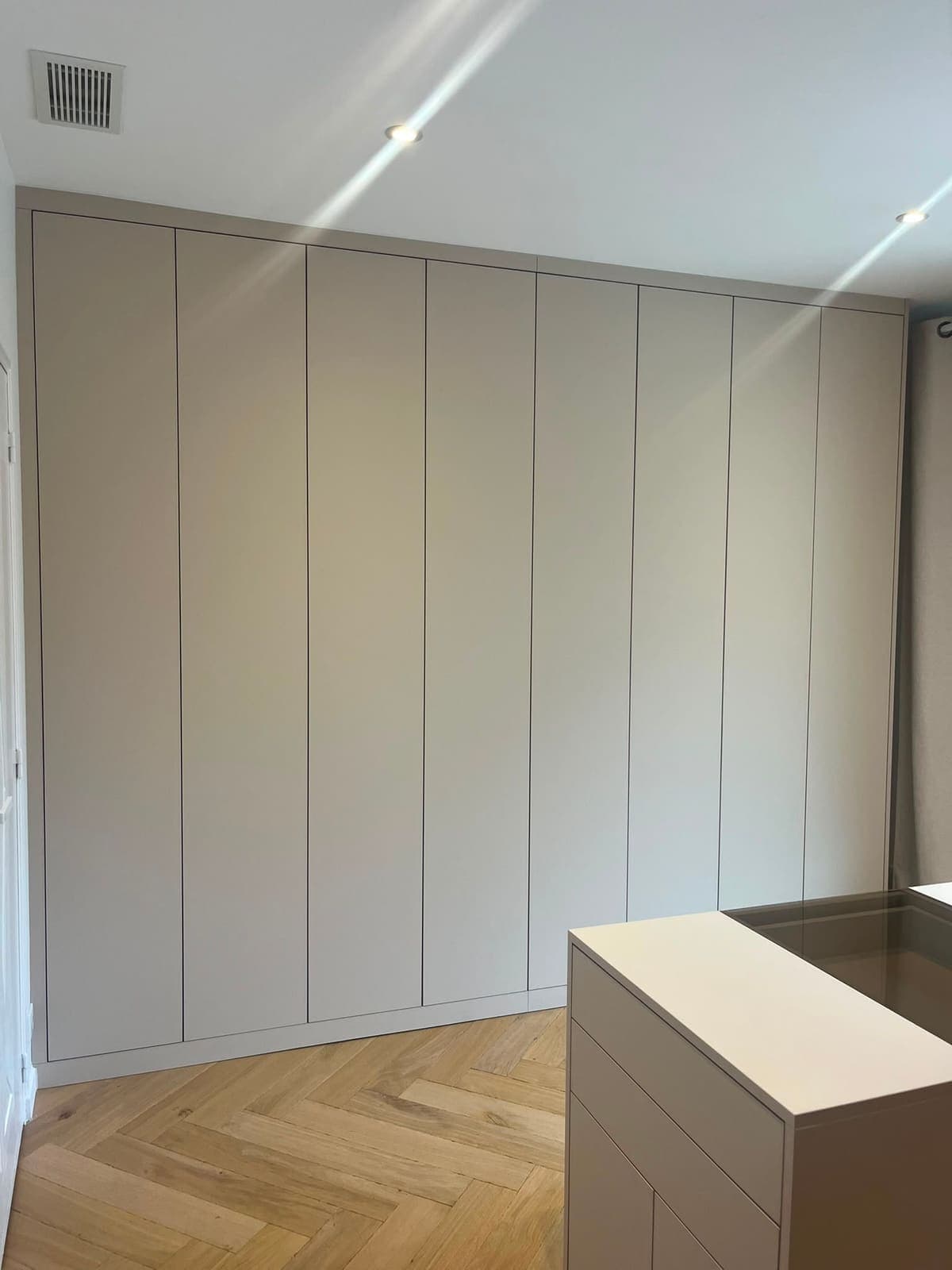 Dressing à façades rainurées occupant un mur entier de chambre, du sol au plafond